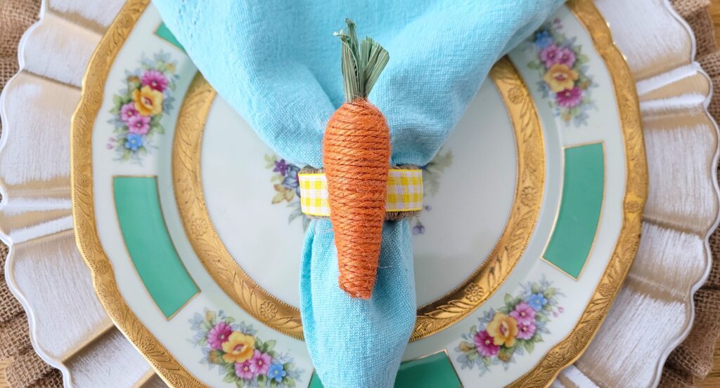 Jute carrot napkin ring with a light blue napkin on a floral plate
