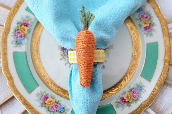 Jute carrot napkin ring with a light blue napkin on a floral plate