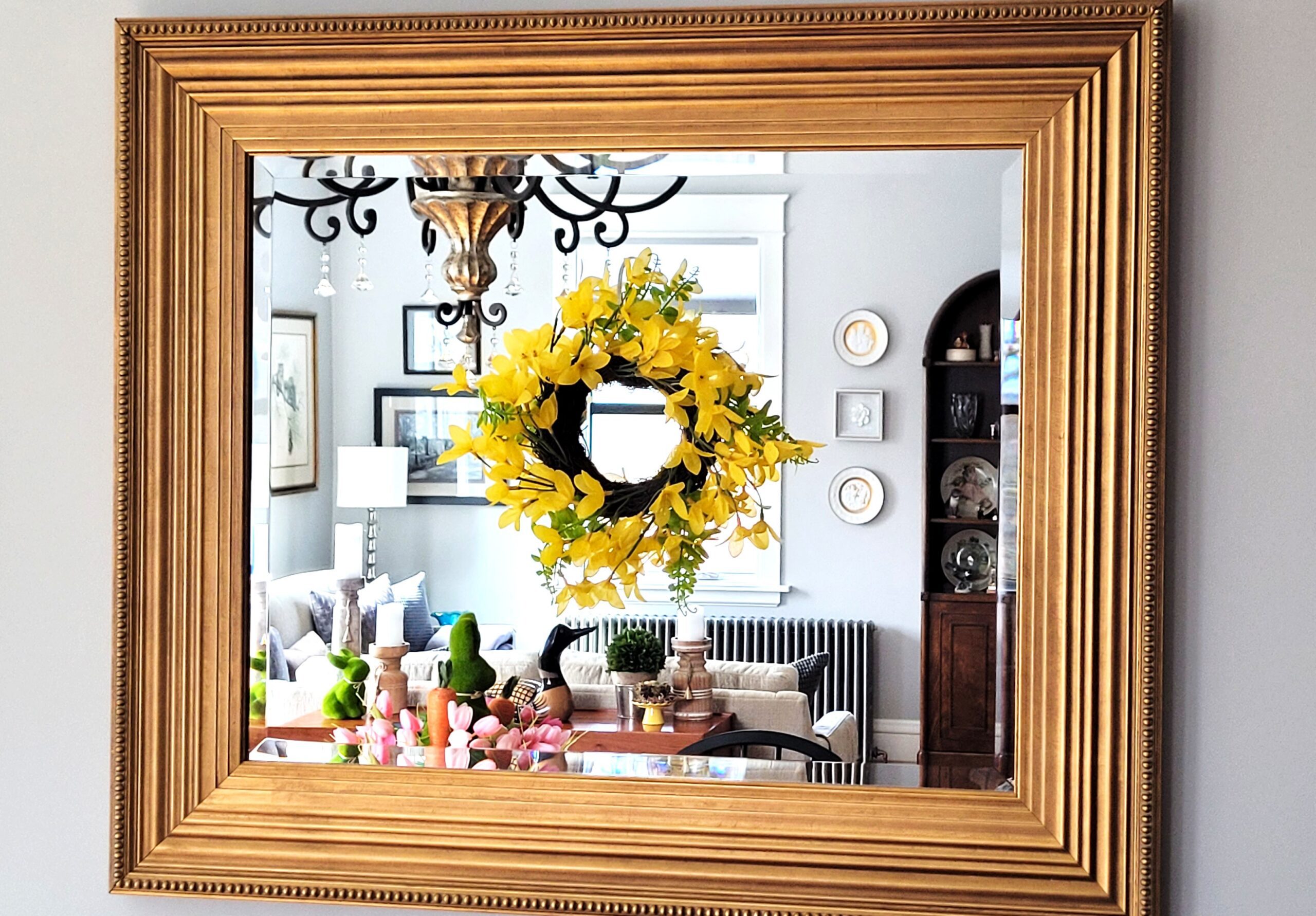 Mini yellow forsythia wreath hung on a gold framed mirror