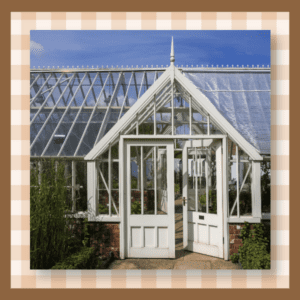 Glass greenhouse with double doors framed in white.