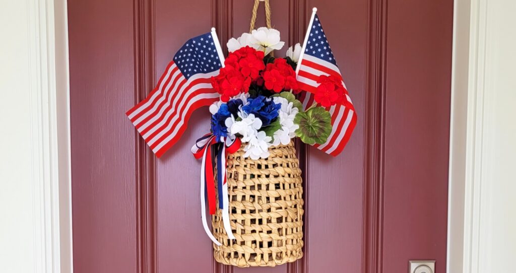 Memorial-Day-Front-Door-3a | The Granite Acorn Woven basket with red white and blue flowers and two small american flags on a maroon door behind it