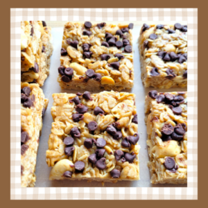 Closeup of two peanut butter chocolate chip granola bar squares They are set on a piece of parchment paper with more granola bars on either side