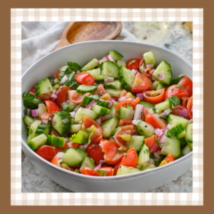 Cucumber-Tomato-Salad-Recipe | The Granite Acorn White bowl filled with chopped cucumbers tomatoes and red onion in a vinaigrette dressing